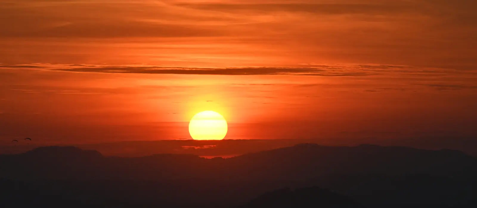 The sun rising over hills and haze, seen from Pratumnak.